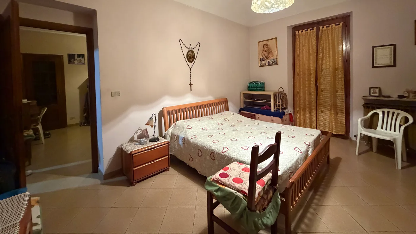 Camera da letto matrimoniale con porta finestra sul balcone, sgombrata e aperta alla luce (prima)