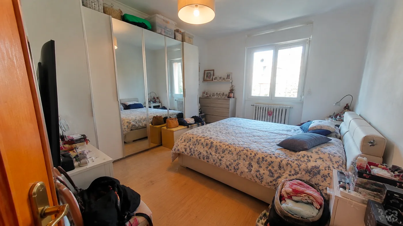 Camera da letto con armadio a specchi e parquet chiaro, sgombrata e rifatta (prima)